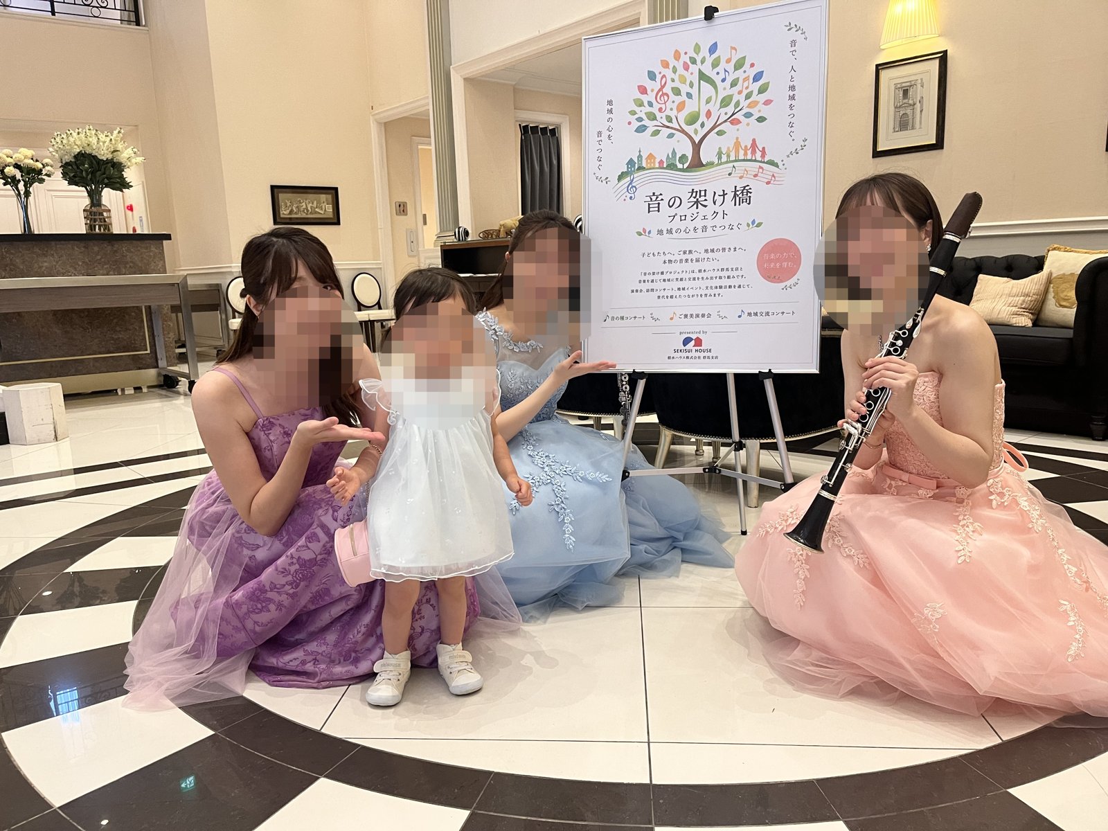 音の架け橋プロジェクトのポスター前でキリトモアンサンブルの演奏者と記念撮影する娘